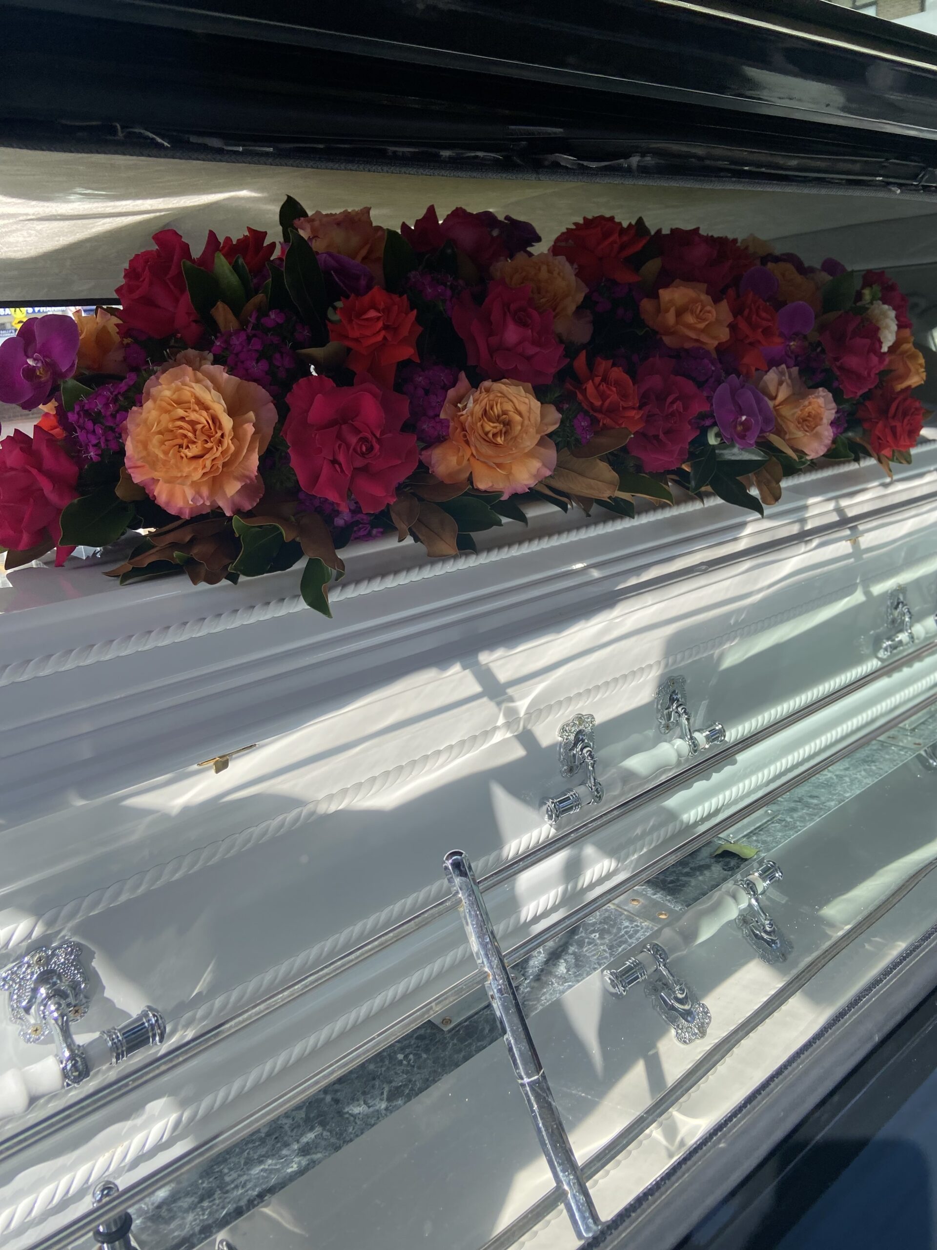 White Coffin in hearse with flowers